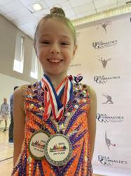 Gymnast smiling with two Philly Love Cup medals around her neck