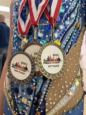 First and second place Philly Love Cup medals resting on a crystal competition leotard