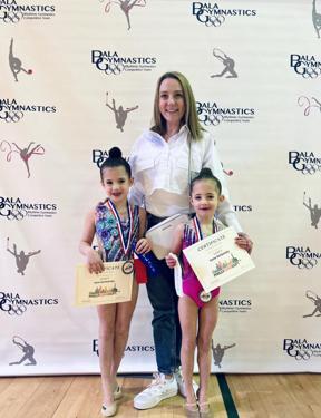 Coach Olena with two gymnasts holding their competition certificates