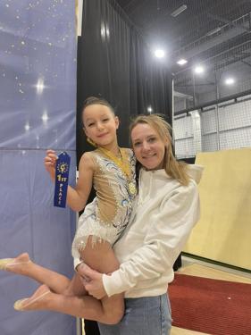 Coach celebrating with a gymnast holding her first place ribbon